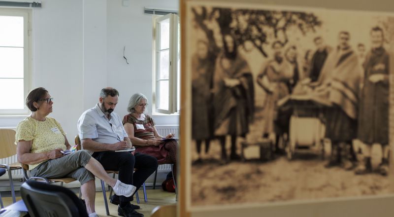 Teilnehmende des Forums der 2. und 3. Generation in einer Kleingruppe; im Vordergrund historische Fotografie